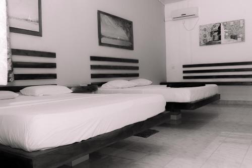 two beds in a room with white walls at Eco Hotel Black & White - Anuradhapura in Mihintale