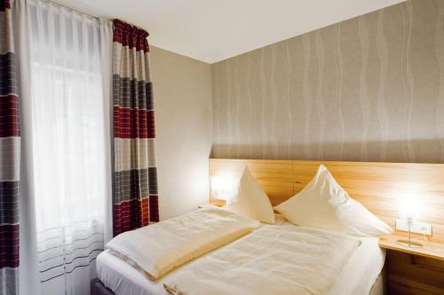 a bedroom with a bed with white sheets and a window at PlusNaturHotel direkt am Ederseeufer Waldhotel Wiesemann und Ferienapartments in Waldeck