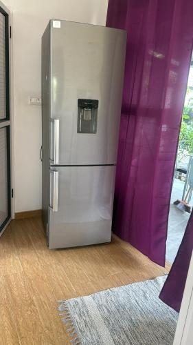 a stainless steel refrigerator in a room with purple curtains at Grand Baie la Croisette villa du bonheur Chez Marie in Hermitage