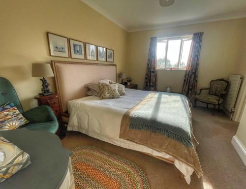 a bedroom with a bed and a chair and a window at Cherryford House in Gidleigh