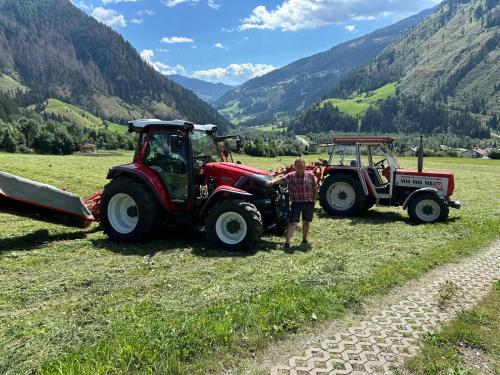 a man standing next to a tractor in a field at Mölltaler Ferienhäuser in Großkirchheim