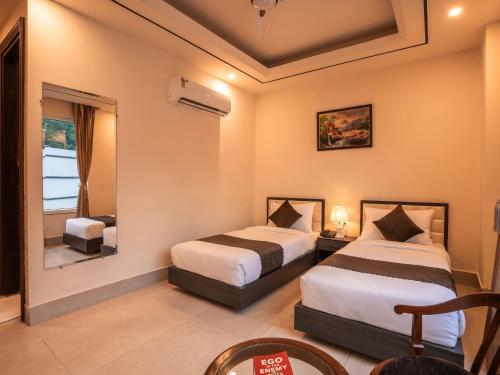 a hotel room with two beds and a mirror at Moustache Rishikesh Luxuria in Rishīkesh