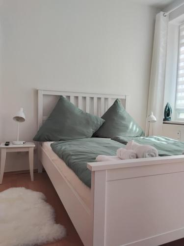 a white bed with green sheets and pillows at Ferienwohnung am Bahnhof Meierstr 43 in Lübeck