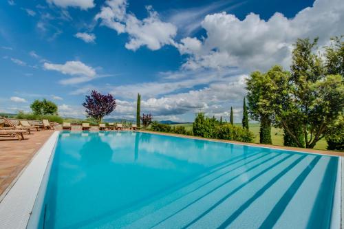 a large swimming pool with blue water and trees at Agriturismo Poggio Istiano in Bagno Vignoni