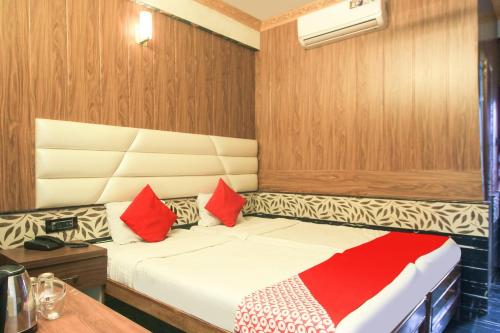 a small bedroom with a bed with red and white pillows at Hotel O Krishna Guest House Siliguri Railway Station in Panchanai