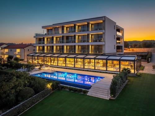 a large building with a swimming pool in front of it at Hotel Villa Margaret in Malinska