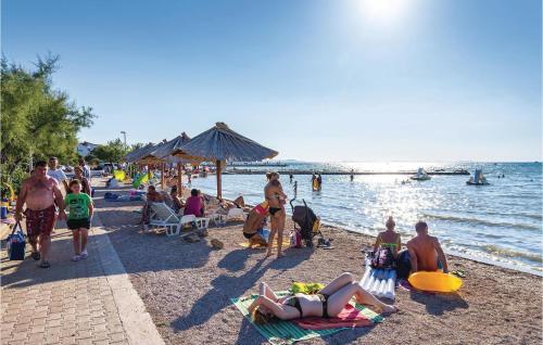 a group of people sitting on the beach at Apartment Maslenica in Jasenice
