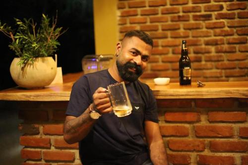 a man sitting at a bar holding a glass at The Coconut Experience Eco Lodge Wilpattu 