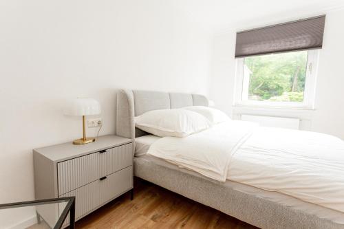 a white bedroom with a bed and a window at Ferienhaus Arina in Bad Bertrich