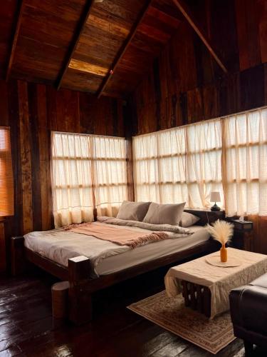 a large bed in a room with wooden walls and windows at Phu Phop Kham in Ban Huai Khai
