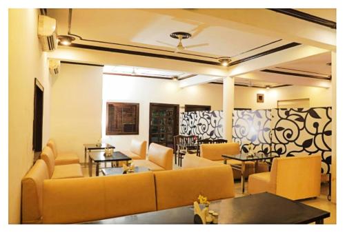 Una sala de estar con sofás y mesas en una habitación. en Hotel Temptation Ultimate Prayagraj AC NR NON AC Both Room, en Prayagraj