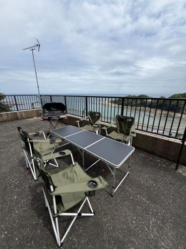 a ping pong table and chairs on a balcony overlooking the water at Kamogawa Sunset Villa - 鴨川サンセットヴィラ in Kamogawa