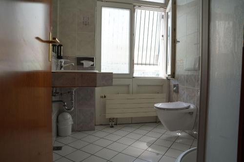 a bathroom with a toilet and a sink and a window at Hotel Porta Nigra VICTUS in Trier