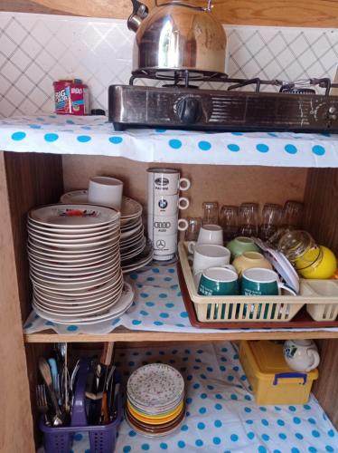 a kitchen pantry with plates and dishes on a shelf at House in forest in Gomi