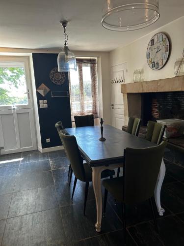 a dining room with a table and chairs and a fireplace at La Maison du Marinier in Crouzilles