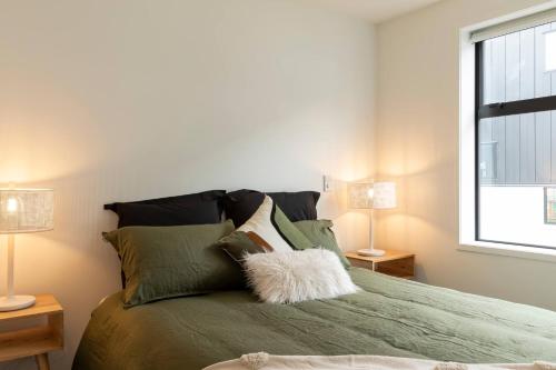a bedroom with a green bed with two lamps at Luxury Apartment Christchurch Central in Christchurch