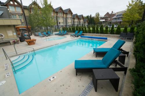 a large swimming pool with blue lounge chairs in a building at Aava Whistler Hotel in Whistler