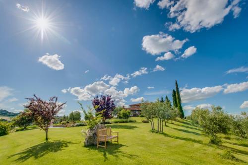 a park with a bench and the sun in the sky at Agriturismo Poggio Istiano in Bagno Vignoni