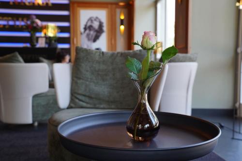 a vase with a rose in it sitting on a table at Hotel Porta Nigra VICTUS in Trier