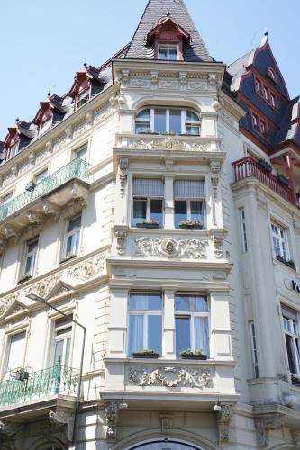 a tall white building with windows and a roof at Hotel Porta Nigra VICTUS in Trier
