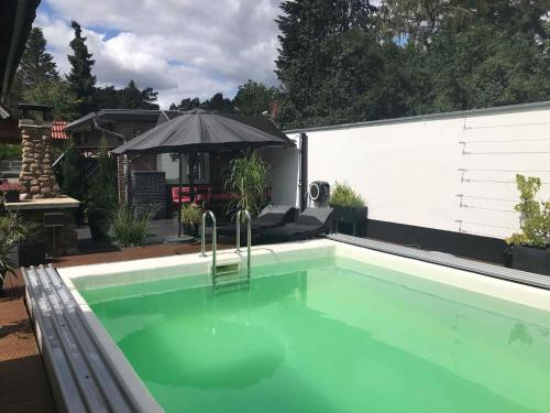 a swimming pool with green water in a backyard at Holiday home in Beelitz 2608 in Beelitz