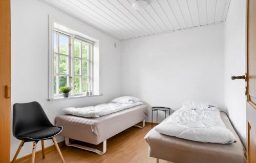 two beds in a room with a chair and a window at 3 Bedroom Beautiful Home In Videbæk in Videbæk