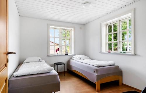 two beds in a room with two windows at 3 Bedroom Beautiful Home In Videbæk in Videbæk
