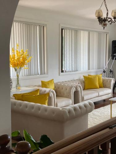 a living room with a white couch and yellow pillows at Bradburry Lovely The Outlook in Campbelltown South