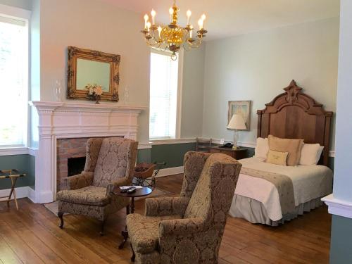 a bedroom with a bed and two chairs and a chandelier at Hale Springs Inn in Rogersville