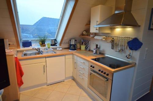 a kitchen with a sink and a stove and a window at Haus Mühlentrift, FeWo 08 in Döse
