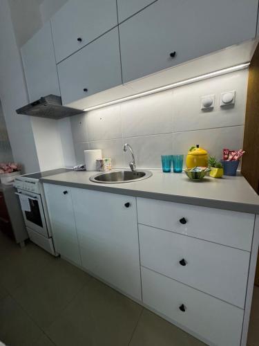 a kitchen with white cabinets and a sink at SpaNish apartman 6 in Niš