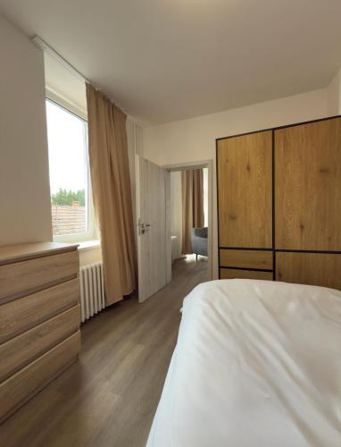 a bedroom with a white bed and a large window at Apartmány Hviezdoslavova in Piešťany