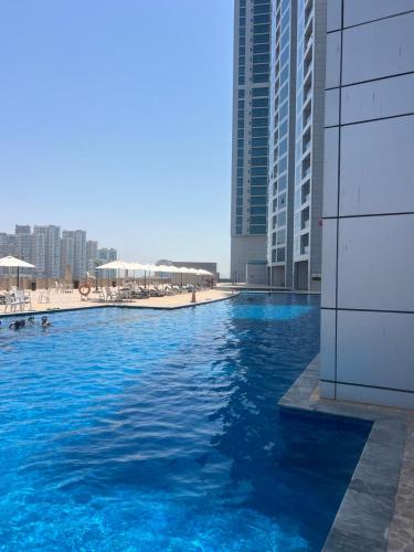 a swimming pool with blue water in front of buildings at Beachfront Paradise - Ajman Corniche Residence in Ajman