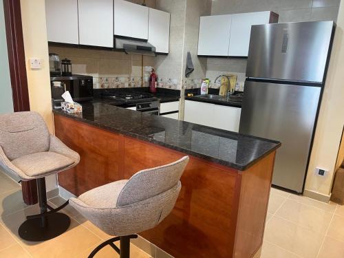- une cuisine avec un comptoir, un réfrigérateur et une chaise dans l'établissement Beachfront Paradise - Ajman Corniche Residence, à Ajman