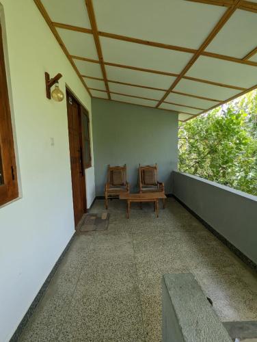a porch with two chairs and a bench on a house at Eco Hotel Black & White - Anuradhapura in Mihintale