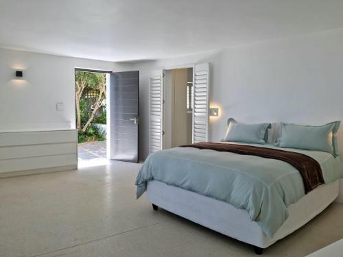 ein weißes Schlafzimmer mit einem großen Bett mit blauen Kissen in der Unterkunft 'Kaya Moya' - Luxury Suite for 2 with Ocean Views in Gordonʼs Bay