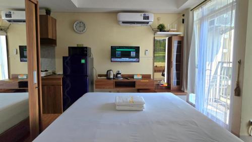 a room with a bed and a kitchen with a tv at Studio Apartment JiExpo Kemayoran View -Min Stay 3 nights- in Jakarta