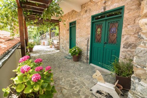 a green door on a stone house with flowers at Anastou's Traditional House in Kalopanayiotis