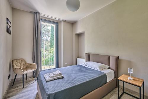 a bedroom with a bed and a chair and a window at Villa Adriana in Lierna