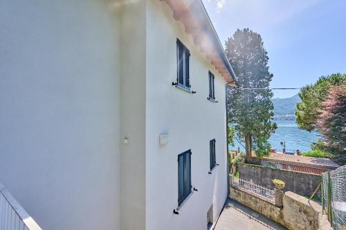 a white building with three windows and a view of the water at Villa Adriana in Lierna