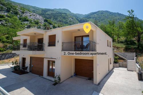 a building with two garage doors with mountains in the background at Red Hill in Kotor