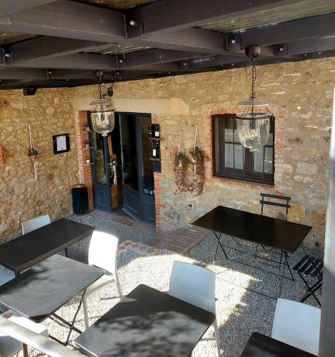 a patio with tables and chairs and a brick wall at Le Stanze del Ritrovino in Castiglione dʼOrcia
