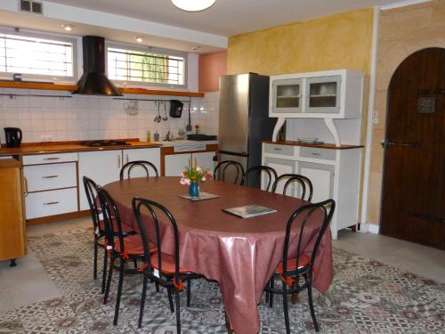 une cuisine avec une table avec des chaises et un réfrigérateur dans l'établissement La Métairie de Lamourade, gîte nature, à Saint-Ferriol
