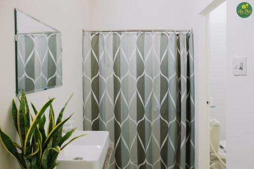 La salle de bains est pourvue d'un rideau de douche et d'une plante. dans l'établissement An Thư Home Garden, à Hue