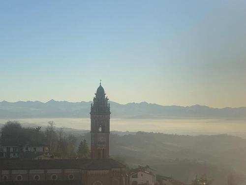 a clock tower on top of a building with mountains in the background at Linda's house in Monforte dʼAlba