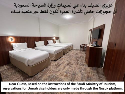 a hotel room with three beds and a sign on the wall at Palestine Hotel Makkah in Makkah