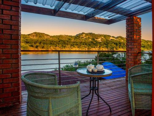 a deck with a table and chairs and a view of a lake at Dungbeetle River Lodge in Colchester