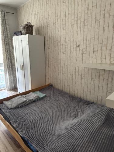 an empty bed in a room with a refrigerator at Centrum Apartament in Gdańsk