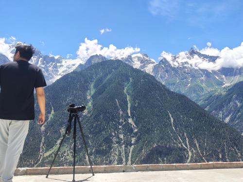 a man standing in front of a camera on a tripod at Whistling Pines Homestay in Kalpa