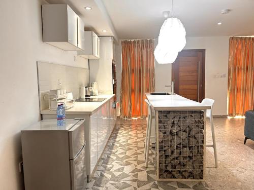 a kitchen with white countertops and an orange curtain at Urban One Luxury Apartments, Kumasi - Gye Nyame in Kumasi